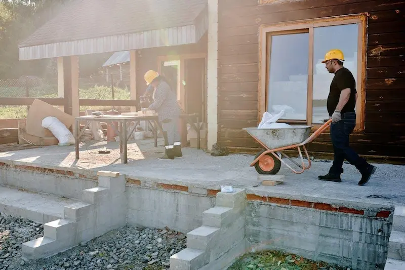 Builders working on a backyard granny flat site showing utility connections